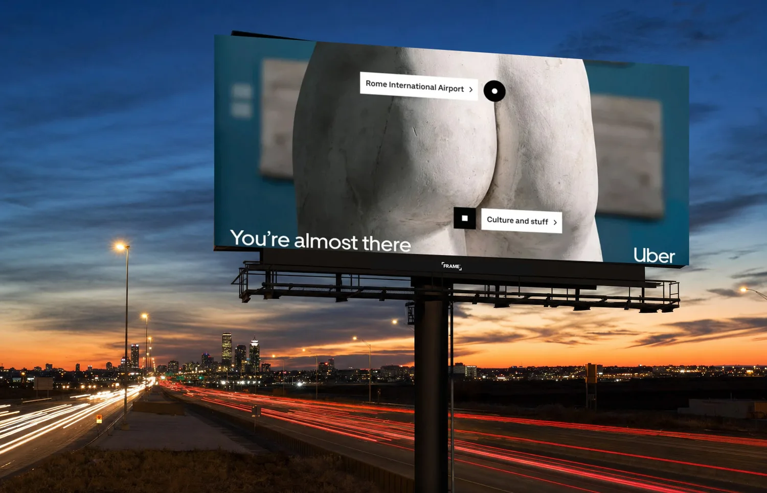 Uber creative on a highway digital billboard at dusk, FRAME nameplate bottom-center on the frame